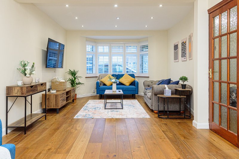 Bright living room with blue sofa, wooden flooring, large windows and contemporary furniture