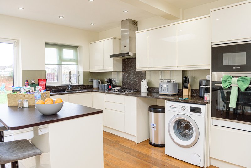 Modern kitchen with white cabinets, dark countertops, island seating, and stainless steel appliances