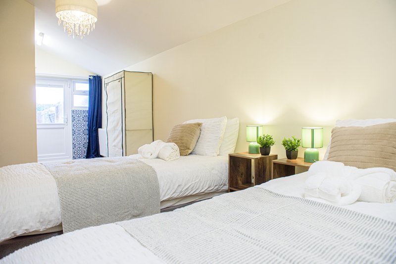 Bright twin bedroom with two single beds, bedside lamps, mirror, window and chandelier