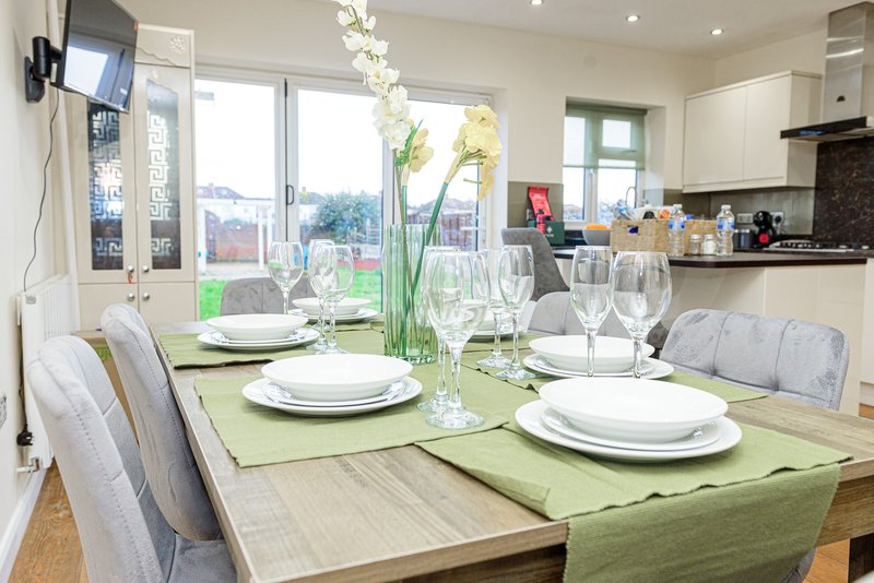 Modern kitchen-diner with dining table set for four, green table runner, and garden view through patio doors