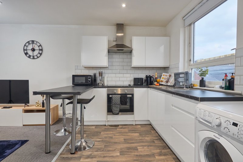 Modern kitchen with white cabinetry, black countertops, stainless steel appliances and waterside view