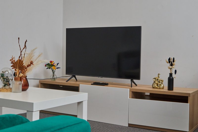 Bedroom with TV mounted on wall, wooden and white media console, decorative items and dried flowers