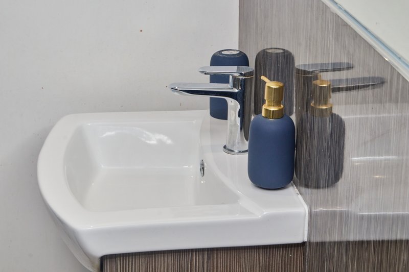 Modern bathroom sink with white basin, chrome faucet, and blue soap dispensers