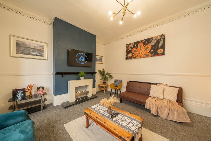 Living room with fireplace, brown sofa, wooden coffee table and modern ceiling light fixture