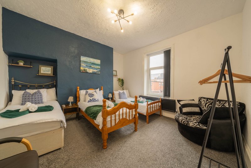 Bedroom with double bed, single bed, dark blue accent wall, window and ceiling light
