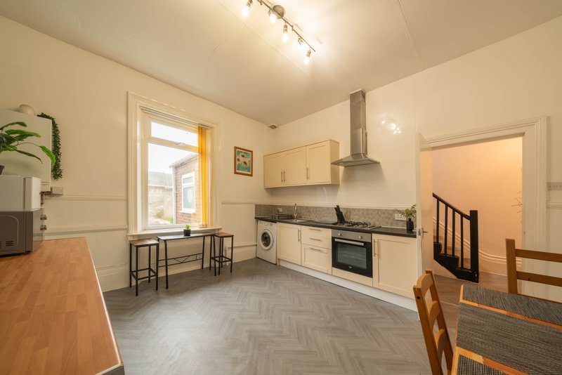 Open-plan kitchen and dining area with cream cabinetry, wooden table, and herringbone flooring