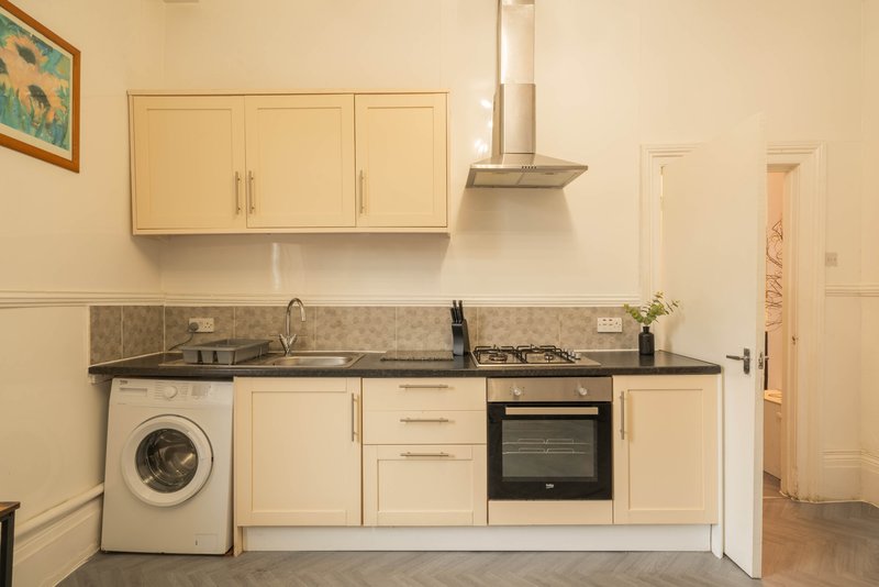 Modern kitchen with cream cabinets, gas hob, oven, washing machine and granite worktop