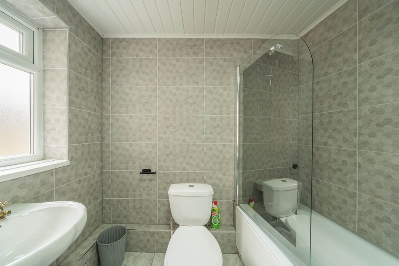 Modern bathroom with toilet, bathtub, shower enclosure, and tiled walls