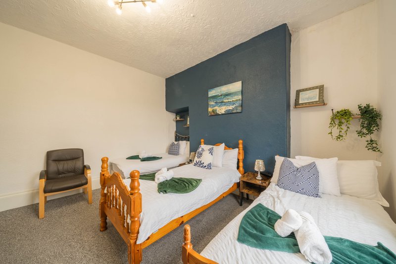 Bedroom with two single beds, blue accent wall, chair, and hanging plants