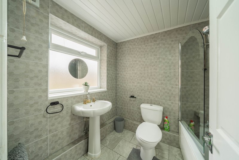 Modern bathroom with pedestal sink, toilet, shower enclosure and window