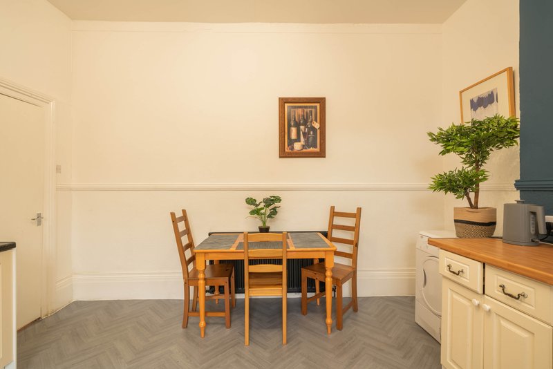 Kitchen-dining area with wooden table, chairs, cream cabinets and potted plant