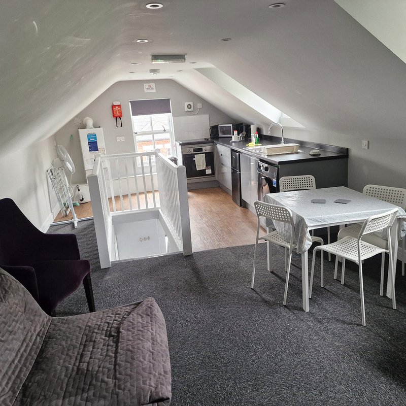 Open-plan attic studio with kitchenette, dining table, seating area and bedroom partition
