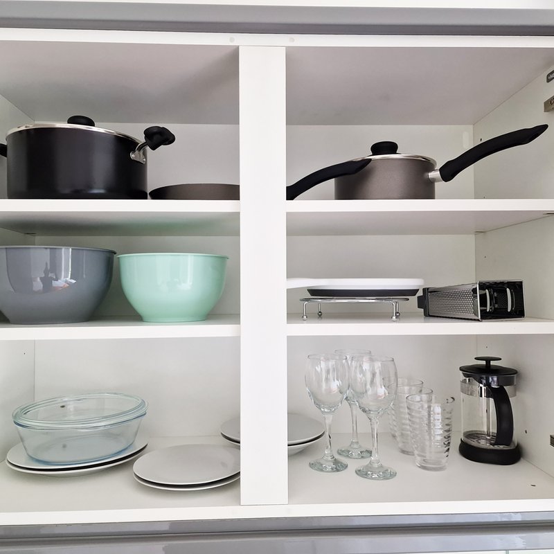 Open shelving unit displaying kitchenware including pots, bowls, glassware, and small appliances