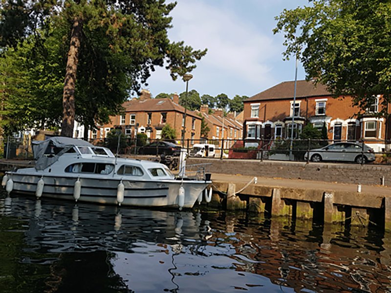 Waterfront property with moored boats, wooden jetty, and brick residential buildings behind