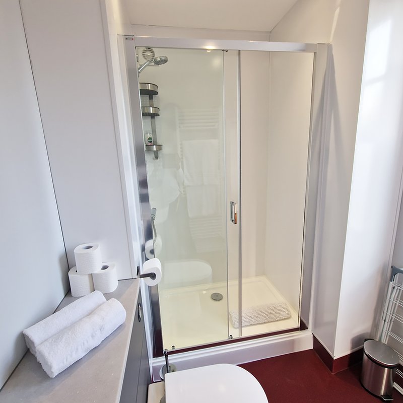 Clean bathroom with shower enclosure, toilet, towels and sink vanity