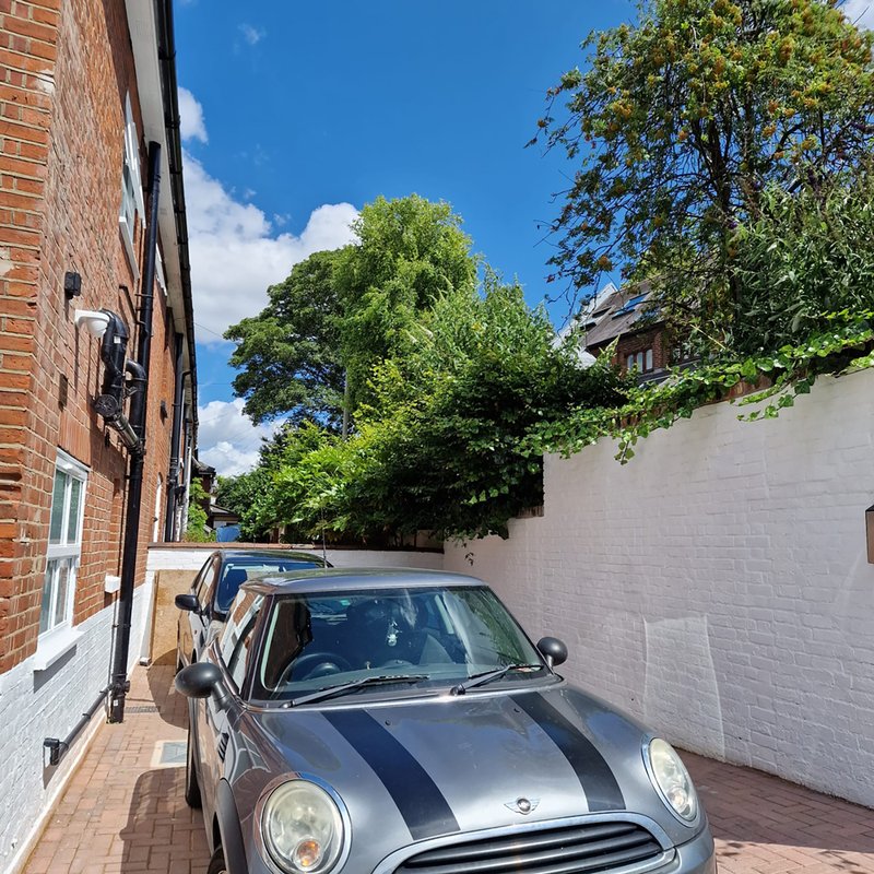 Brick townhouse exterior with parked car, driveway and garden wall