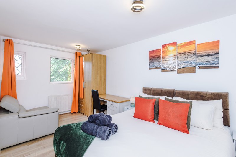Bedroom 1: King Size Zip Link Bed which can be split into 2x single beds - Bright bedroom with double bed, orange accents, seating area and sunset wall art