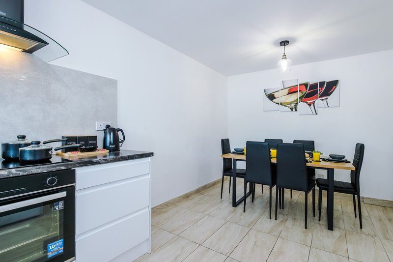 Open-plan kitchen and dining area with white cabinetry, black dining table and chairs