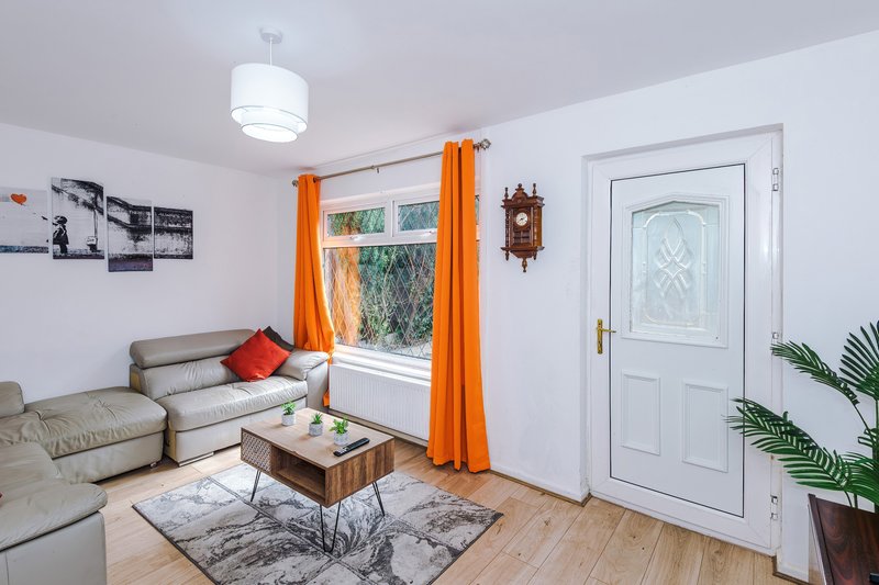 Modern living room with grey sofa, wooden coffee table, orange curtains and wooden flooring