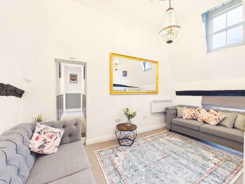 Bright living room with two grey sofas, patterned rug, yellow mirror and pendant light