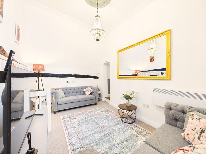 Spacious living room with grey sofa, yellow-framed mirror, pendant light and neutral décor