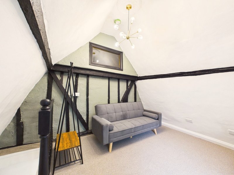 Modern loft bedroom with gray sofa, black metal railing, and pendant light fixture