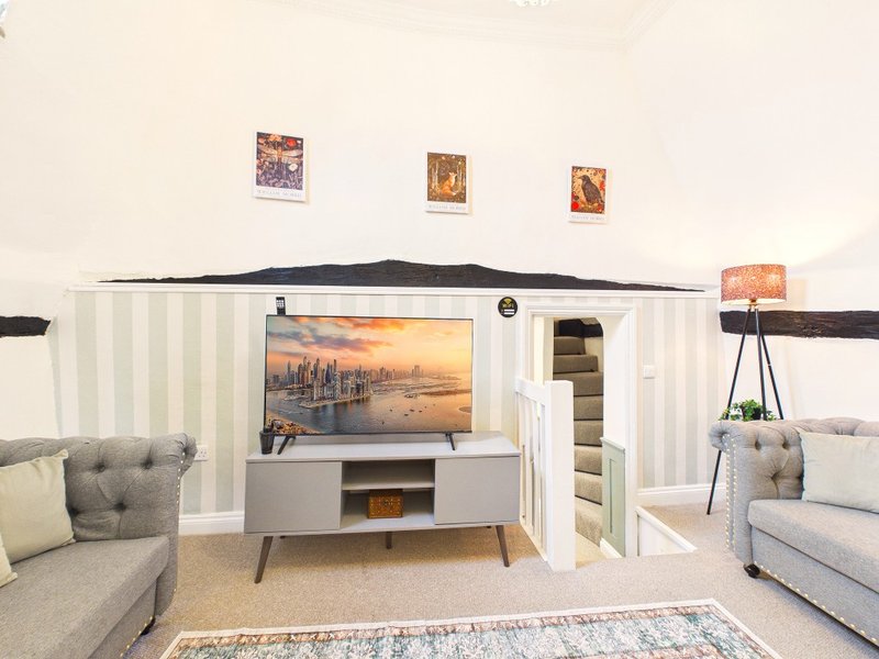 Living room with TV, gray furniture, framed artwork, tripod lamp and neutral decor