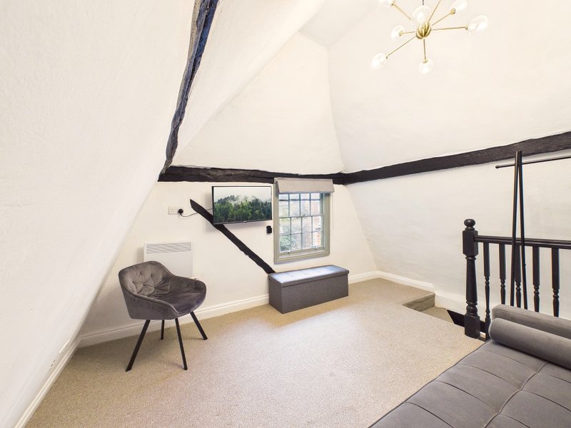 Attic bedroom with sloped ceiling, modern chair, window seat and black railings