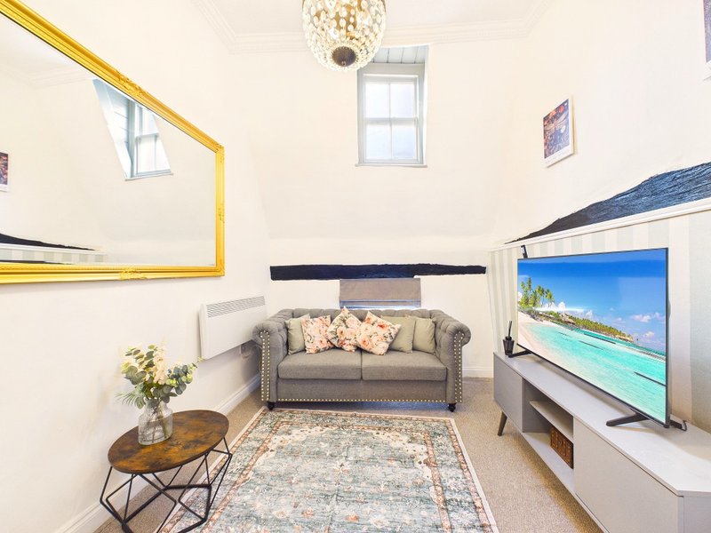 Living room with grey sofa, wooden coffee table, TV, and yellow-framed artwork on wall