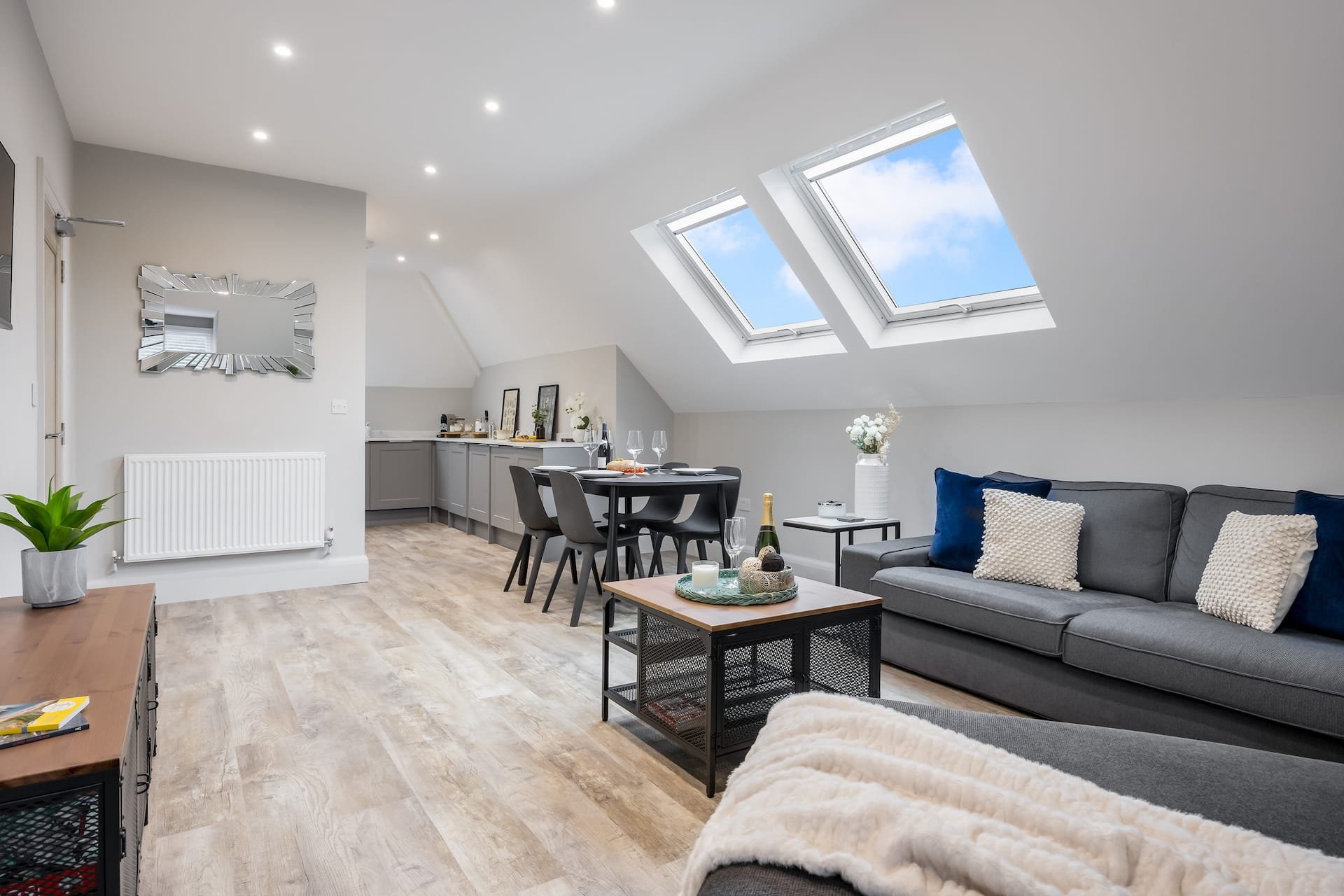 Modern open-plan loft with sofa, dining table, skylights and wooden flooring