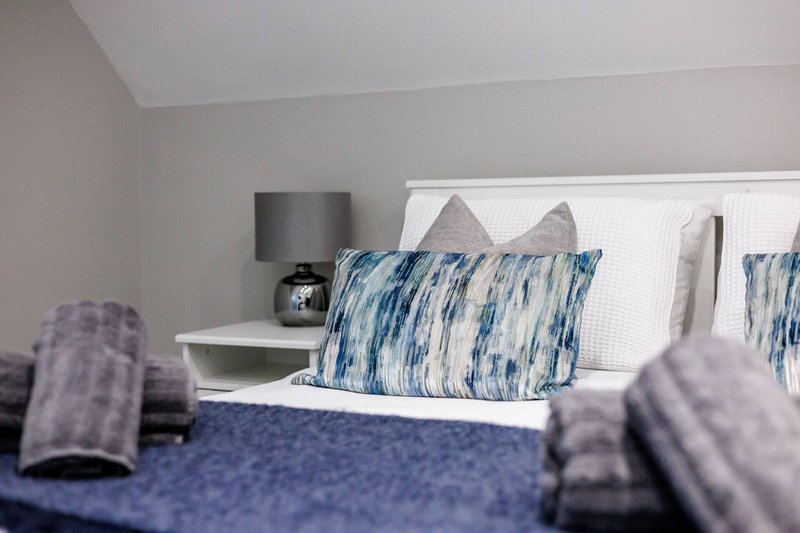 Modern bedroom with blue patterned pillows, white headboard, and bedside lamp