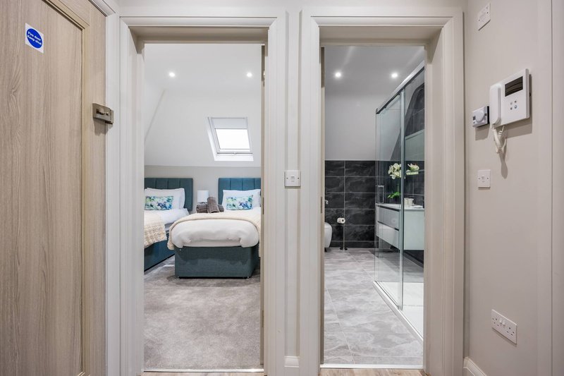 Hallway with open doors showing bedroom and bathroom, light wood frames and neutral tones
