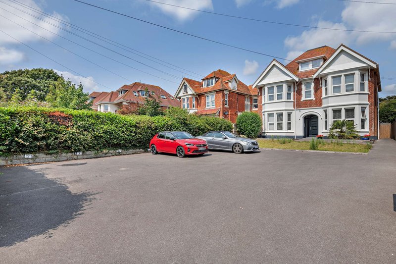 Brick Victorian house with driveway, parked cars, and neighboring properties