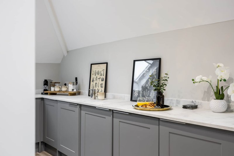 Modern kitchen with gray cabinetry, white countertop, framed wall art, and decorative items