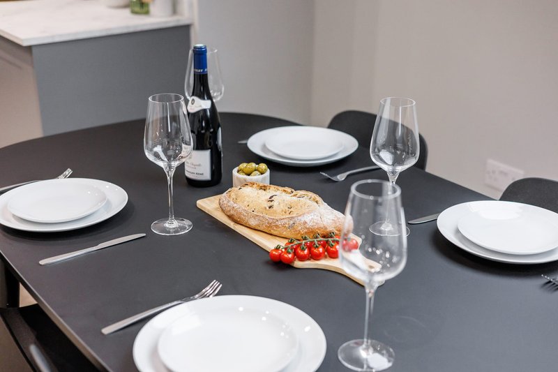 Dining table set for four with plates, glassware, wine bottle and fresh bread