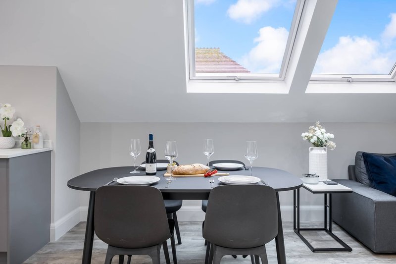 Modern dining area with black table, chairs, skylight windows and white flowers