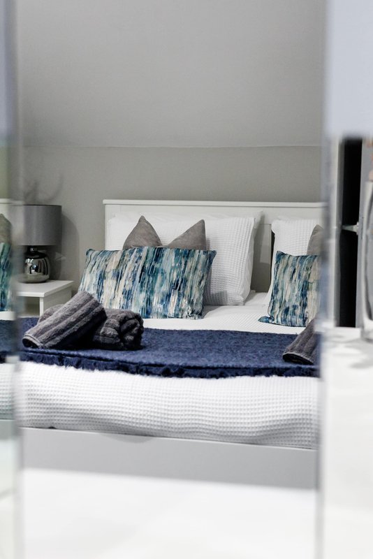 Modern bedroom with white bed frame, blue patterned pillows and navy bedding