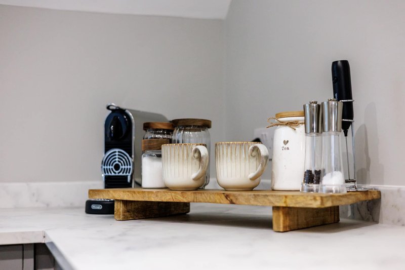 Kitchen countertop with coffee machine, utensil holder, and ceramic containers on wooden tray