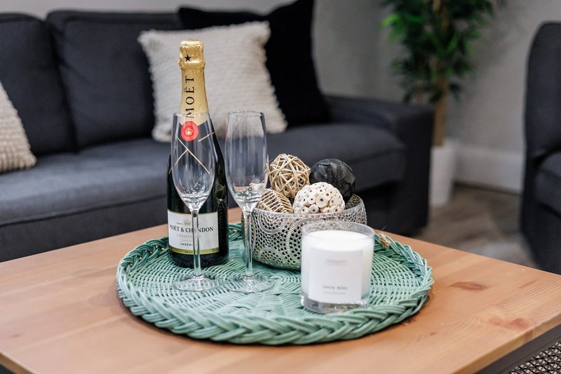 Living room with wooden coffee table styled with champagne bottle, glasses, candle and decorative items