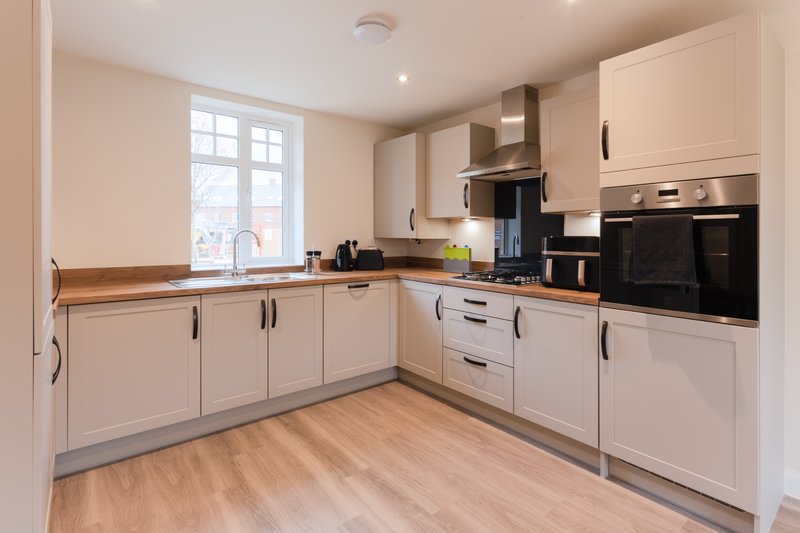 Modern kitchen with white cabinetry, black appliances, wooden worktops and window