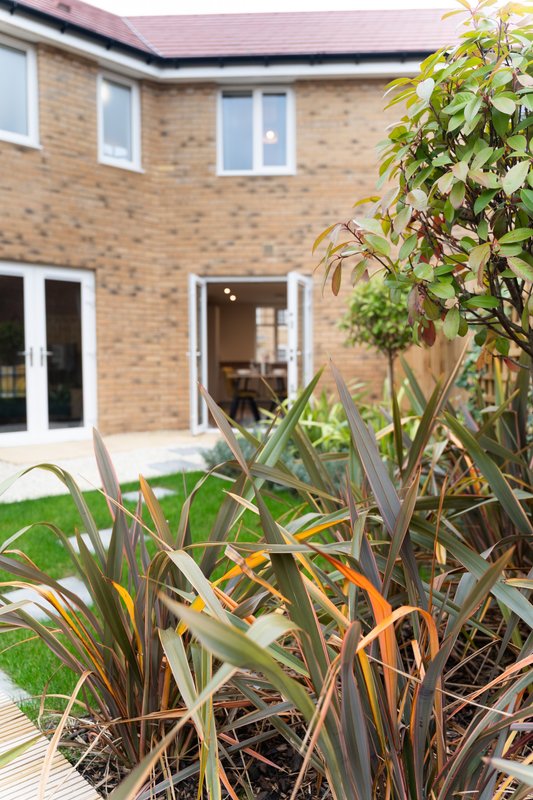 Brick house exterior with garden, patio doors, and ornamental grasses in foreground