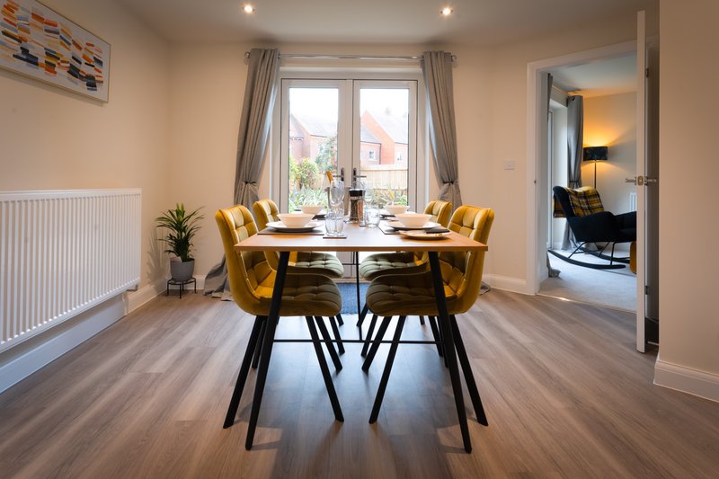 Dining area with round table, gold velvet chairs, large windows and wooden flooring