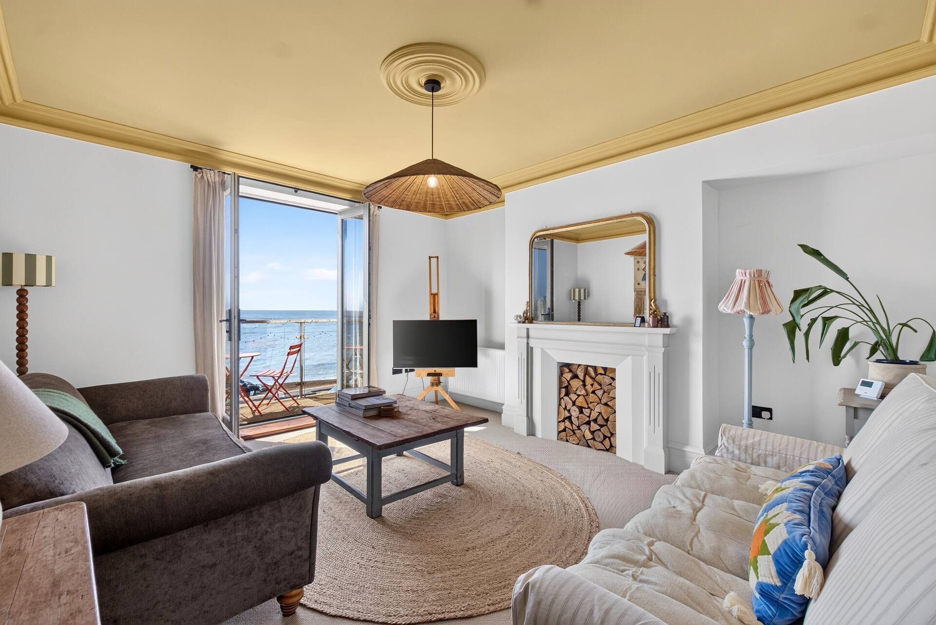 Bright living room with seating, fireplace, ocean view from balcony doors