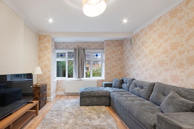 Living room with grey sofa, TV, patterned wallpaper and windows overlooking garden