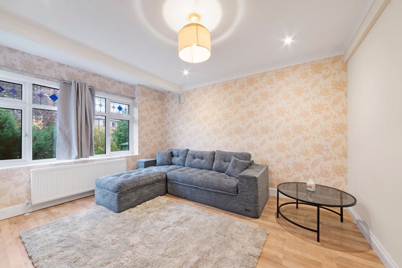 Modern living room with grey corner sofa, wooden floor, patterned wallpaper and large windows