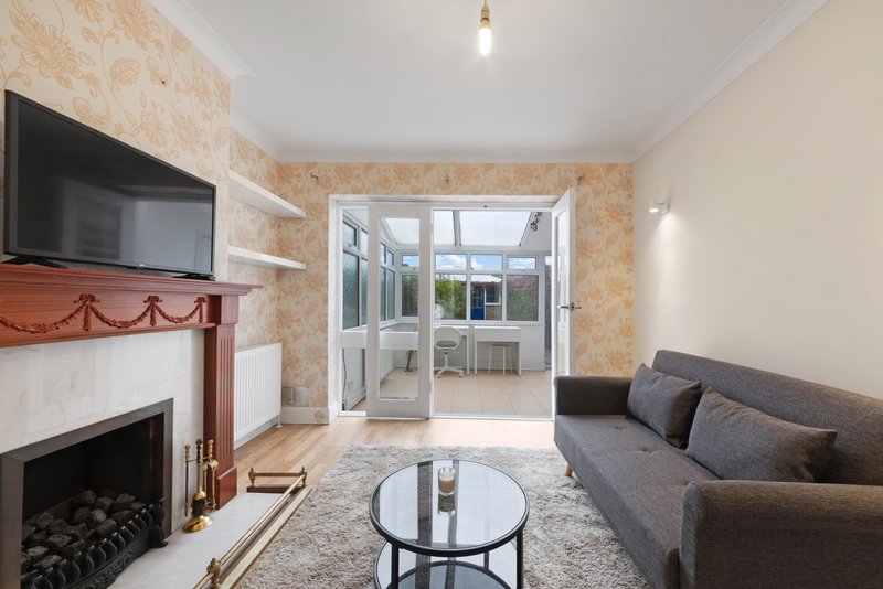 Living room with fireplace, grey sofa, glass coffee table and patio doors to garden