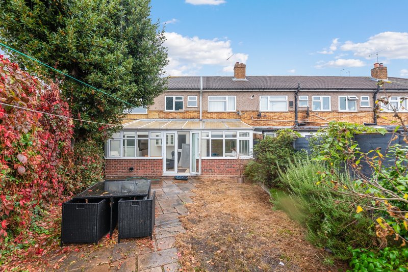 Brick terraced house with modern extension, patio area, garden and bins