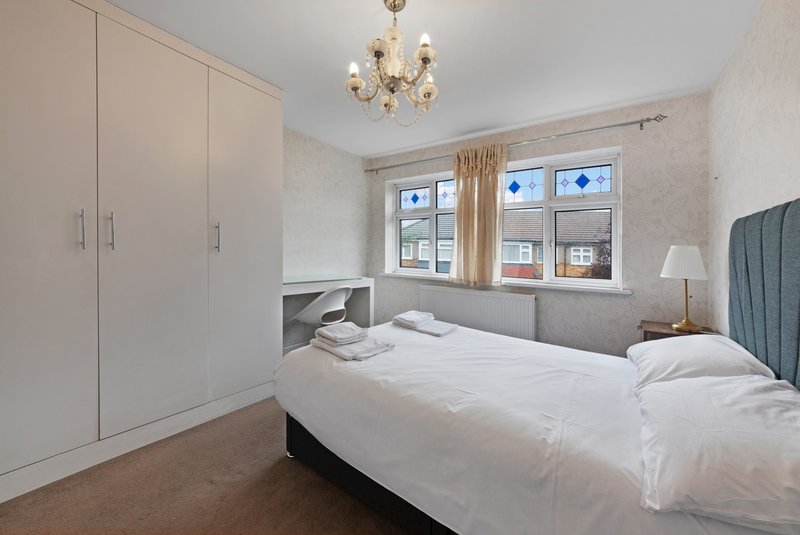Bright bedroom with double bed, white wardrobe, pendant light and windows overlooking street