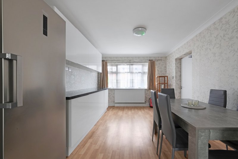 Modern kitchen and dining area with white cabinetry, wooden flooring, and seating for four