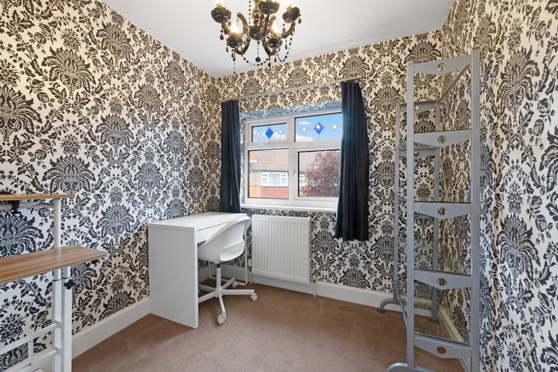 Home office with patterned wallpaper, desk, chair, window and shelving unit